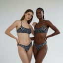 Two models wearing matching animal print bikinis against a plain background